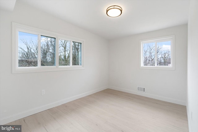 unfurnished room featuring light wood finished floors, visible vents, and baseboards