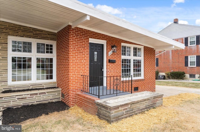 property entrance featuring brick siding and central AC unit