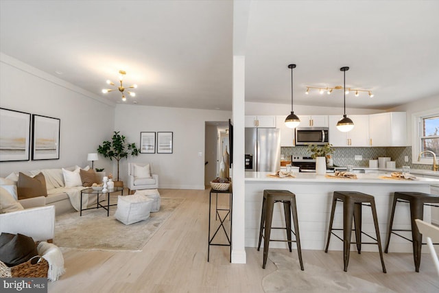 kitchen with a breakfast bar, white cabinets, open floor plan, appliances with stainless steel finishes, and tasteful backsplash