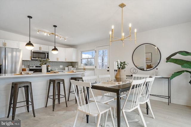 dining area with an inviting chandelier, light wood-style flooring, and lofted ceiling