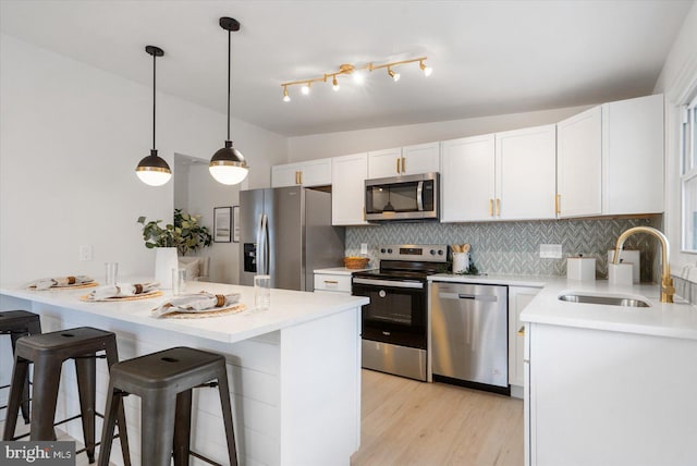 kitchen with a kitchen bar, a sink, white cabinetry, appliances with stainless steel finishes, and vaulted ceiling