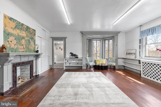 interior space featuring wood finished floors, a tiled fireplace, and crown molding