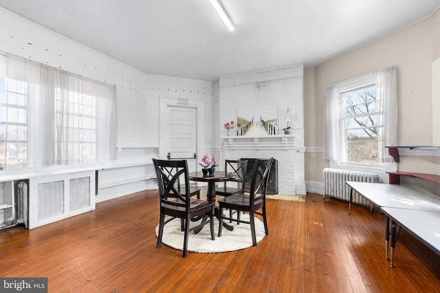 dining room with radiator, a fireplace, and wood-type flooring