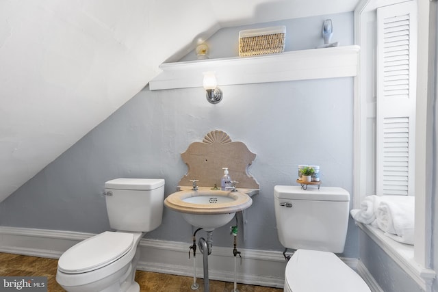 half bath with baseboards, lofted ceiling, and toilet