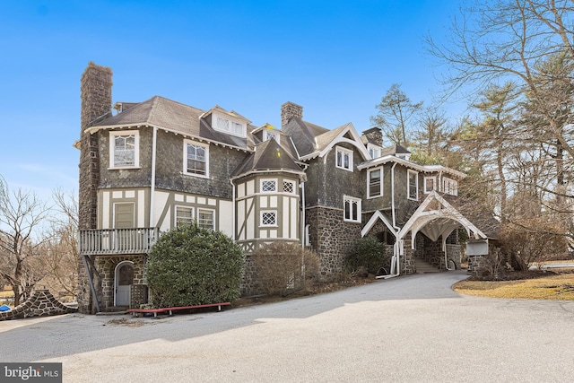 view of front facade featuring stucco siding, stone siding, and a chimney