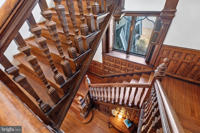 stairs with wood finished floors and wainscoting