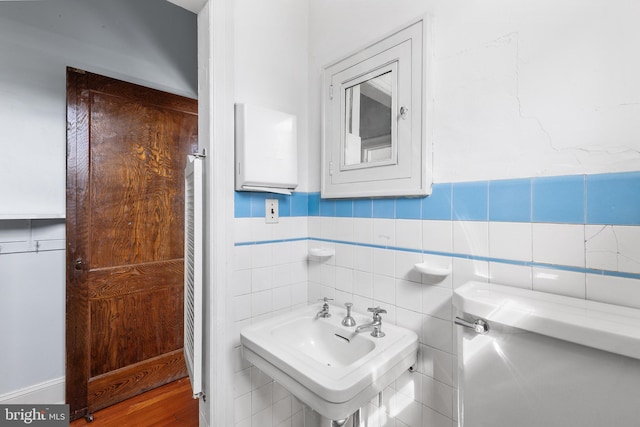 half bathroom featuring a sink, a wainscoted wall, and tile walls