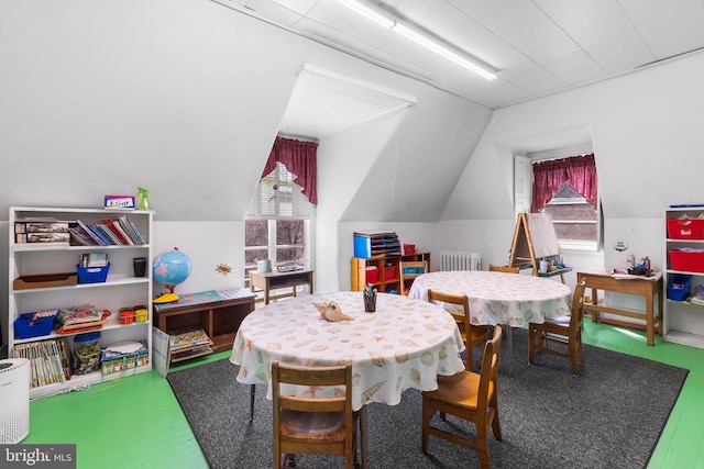 recreation room featuring lofted ceiling and radiator