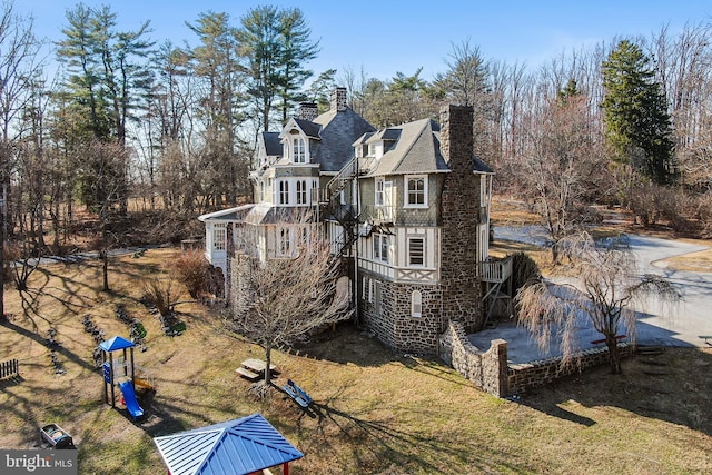 exterior space featuring stone siding, a chimney, and a balcony