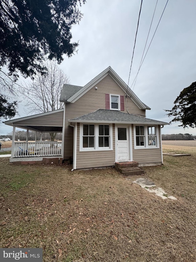 view of front of home featuring an attached carport, a front lawn, and roof with shingles