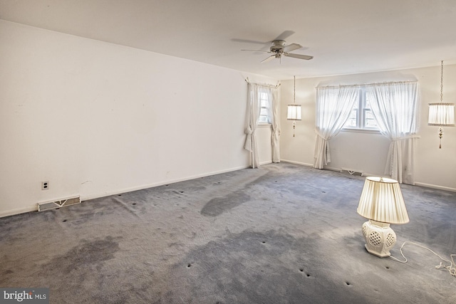 carpeted spare room with visible vents, baseboards, and a ceiling fan