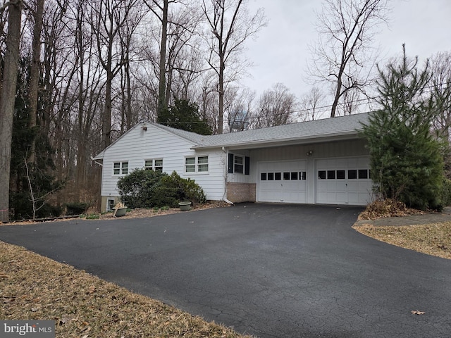 ranch-style house featuring brick siding, driveway, a garage, and roof with shingles