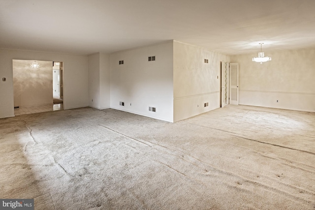 carpeted spare room with visible vents and a notable chandelier