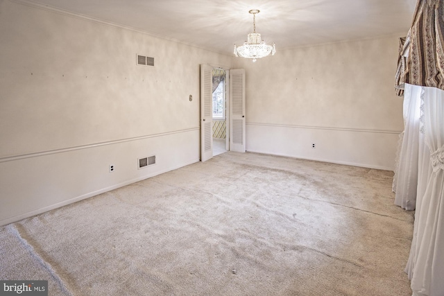 carpeted spare room with a chandelier, visible vents, and ornamental molding