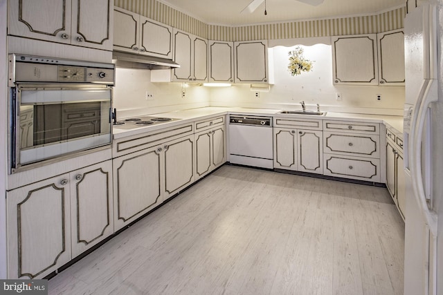 kitchen featuring light wood-style flooring, under cabinet range hood, a sink, white appliances, and light countertops