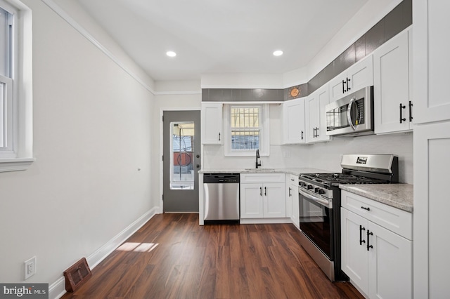 kitchen with visible vents, stainless steel appliances, dark wood-style floors, white cabinetry, and a sink