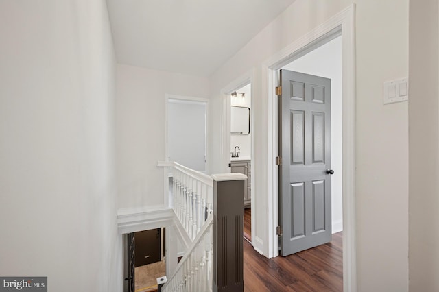 hall with baseboards, an upstairs landing, dark wood-style flooring, and a sink