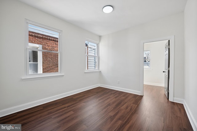 empty room featuring baseboards and dark wood finished floors