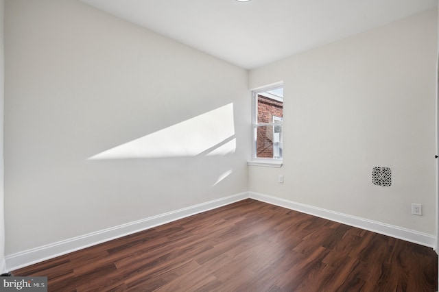 empty room featuring dark wood finished floors and baseboards