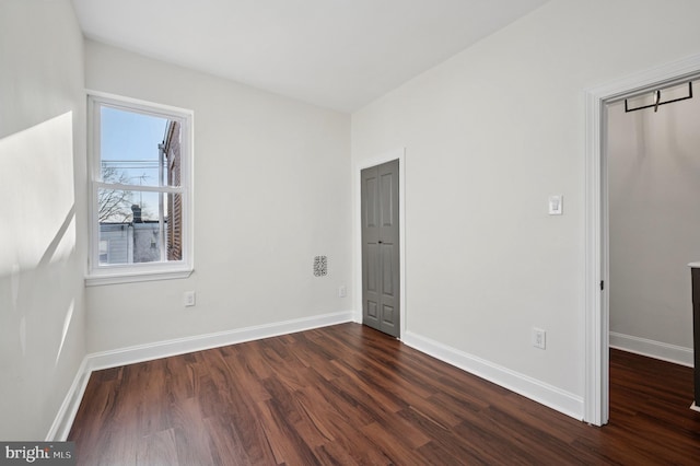 unfurnished bedroom with baseboards and dark wood-style floors