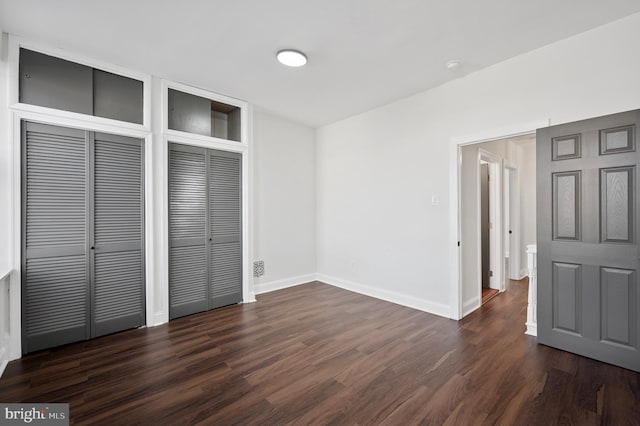 unfurnished bedroom with dark wood-type flooring and baseboards