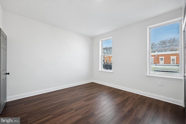 spare room featuring baseboards and dark wood-style flooring