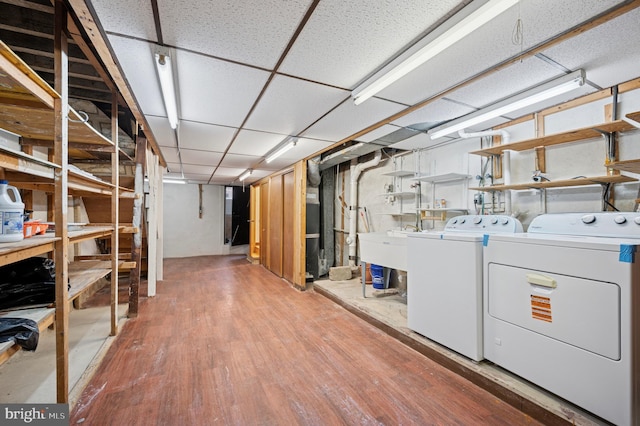 unfinished below grade area featuring a sink, wood finished floors, and washer and clothes dryer