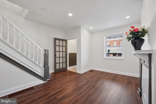 unfurnished living room featuring stairs, wood finished floors, visible vents, and baseboards