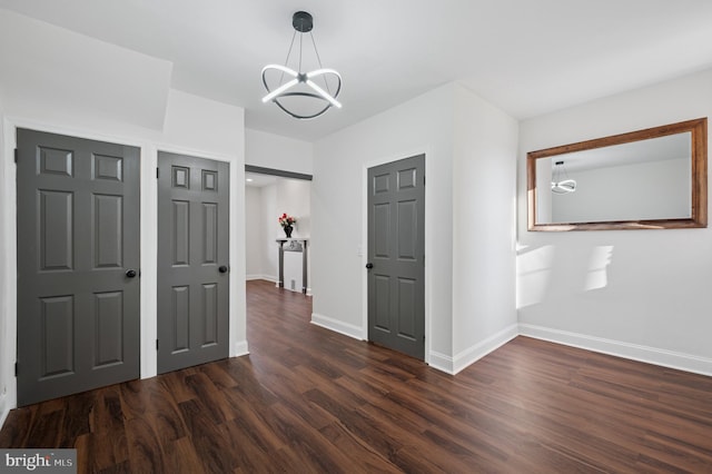 interior space with dark wood-style floors, baseboards, and an inviting chandelier