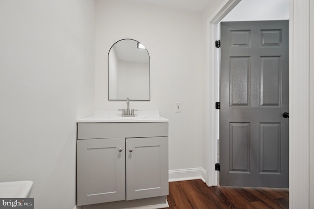 half bathroom featuring vanity, wood finished floors, and baseboards