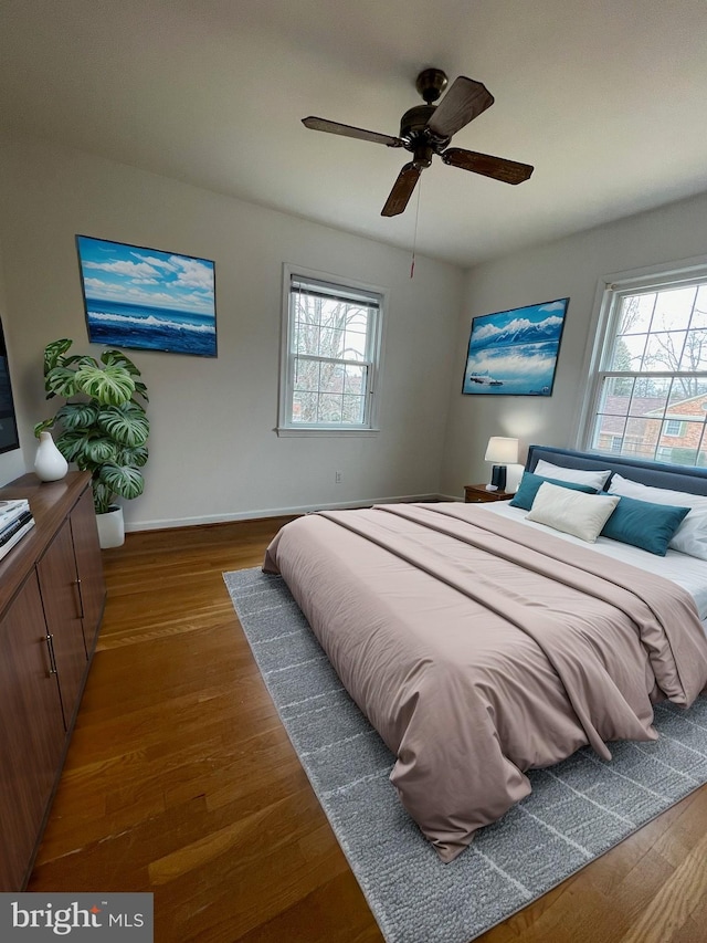 bedroom with multiple windows, ceiling fan, baseboards, and wood finished floors