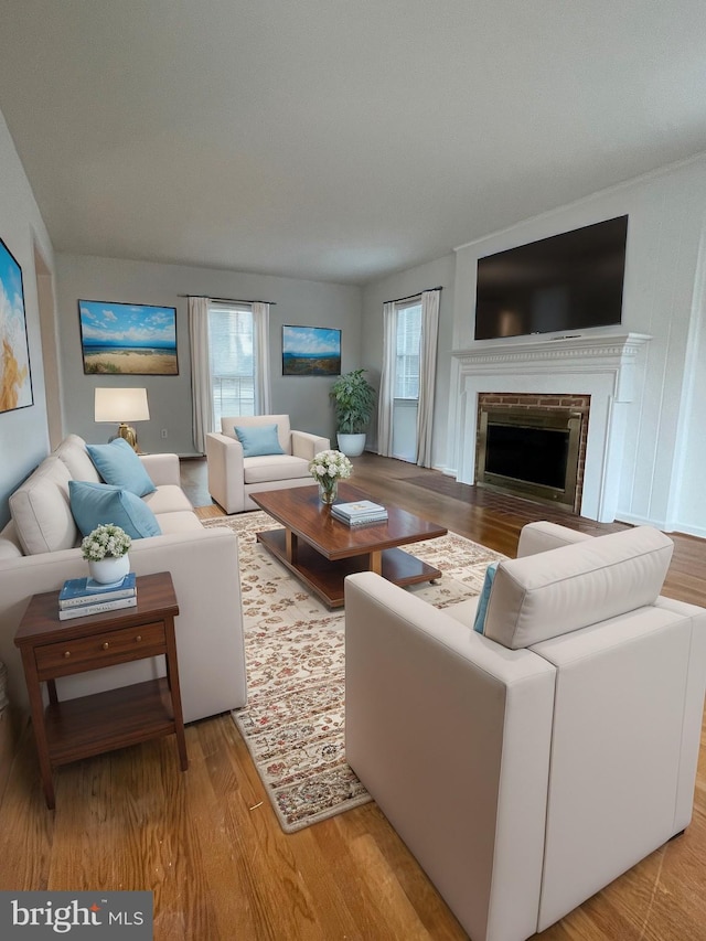 living room with a brick fireplace and light wood-type flooring