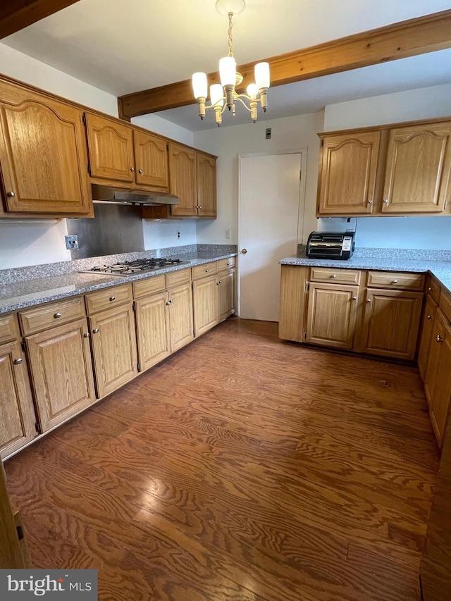 kitchen featuring under cabinet range hood, a chandelier, beam ceiling, stainless steel gas stovetop, and dark wood-style floors