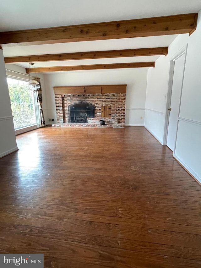 unfurnished living room with dark wood-style floors, beam ceiling, and a fireplace