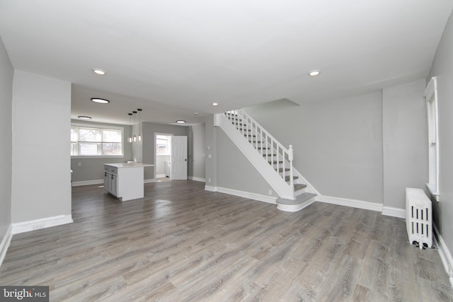 unfurnished living room featuring radiator heating unit, wood finished floors, and baseboards