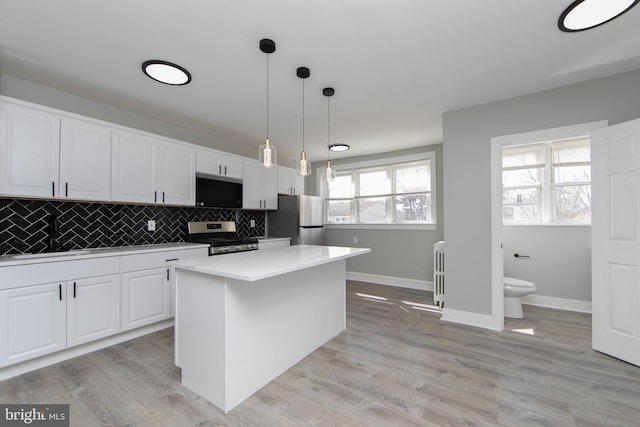 kitchen featuring a sink, decorative backsplash, light countertops, appliances with stainless steel finishes, and white cabinetry