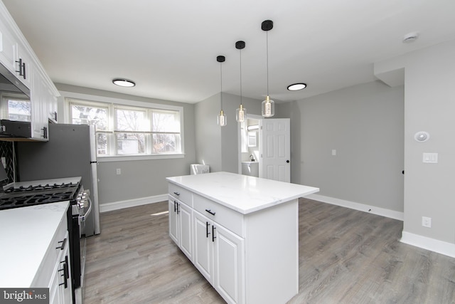 kitchen with a kitchen island, light wood-style floors, white cabinets, and gas range oven