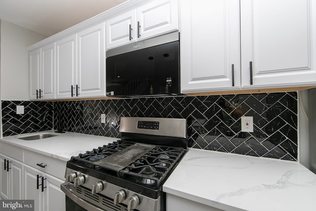 kitchen featuring a sink, tasteful backsplash, stainless steel range with gas stovetop, and white cabinets