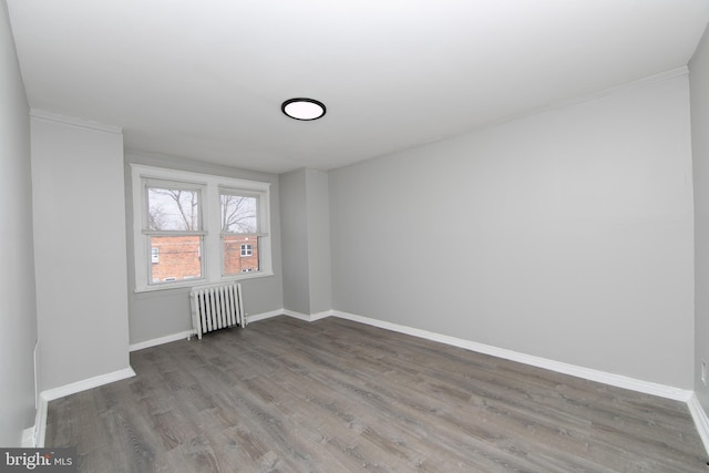 unfurnished room featuring radiator heating unit, baseboards, and wood finished floors