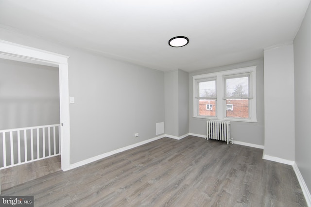 unfurnished room with radiator heating unit, baseboards, and wood finished floors