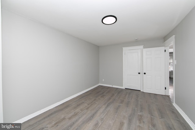 unfurnished bedroom featuring wood finished floors, baseboards, and a closet