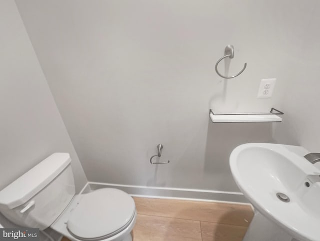 bathroom with toilet, baseboards, and a sink