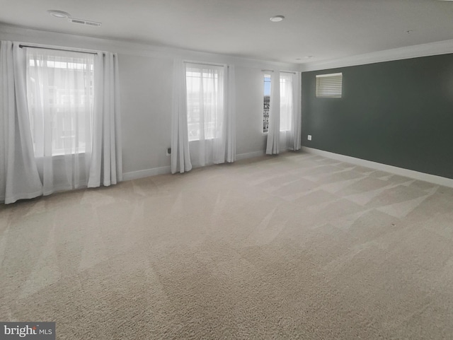 carpeted spare room with visible vents, baseboards, and ornamental molding