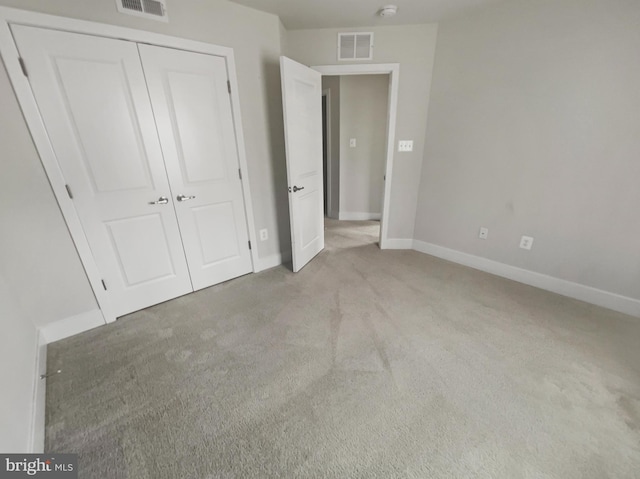 unfurnished bedroom with light carpet, visible vents, baseboards, and a closet