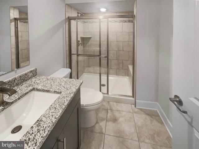 bathroom with tile patterned floors, toilet, a stall shower, baseboards, and vanity