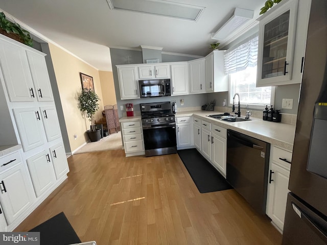 kitchen featuring a sink, stainless steel appliances, light wood-style floors, crown molding, and light countertops