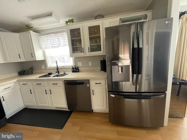 kitchen with light wood-style flooring, a sink, white cabinetry, appliances with stainless steel finishes, and light countertops