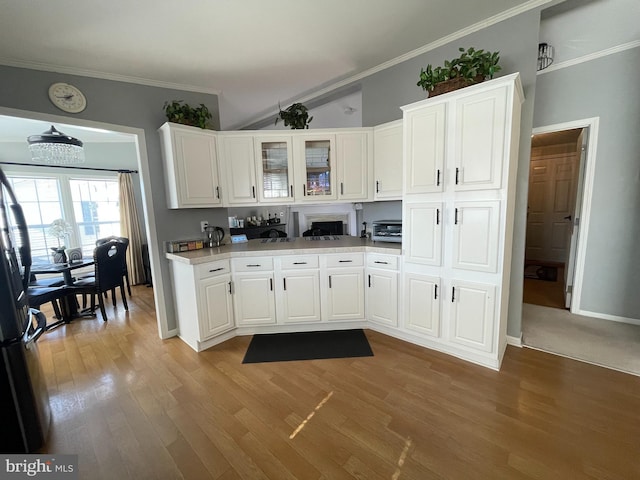 kitchen featuring white cabinetry, light wood-type flooring, light countertops, and ornamental molding