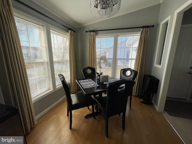 dining area with light wood-type flooring, crown molding, baseboards, a chandelier, and vaulted ceiling