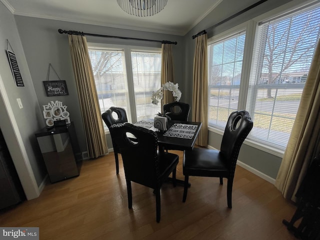 dining area with crown molding, light wood-style floors, and vaulted ceiling